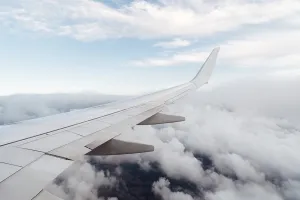 Aviation Industry Images Drucke: Wing of a flying airplane on clouds