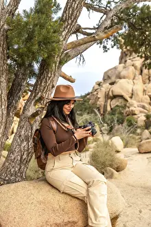 Outdoor Recreation Activities Drucke: Woman sitting under a tree checking her digital camera