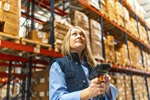 Warehouse Worker Drucke: Woman worker scanning package with bar code reader in a distribution warehouse