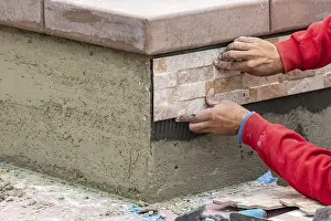 Construction Site Worker Drucke: Worker installing wall tile at construction site