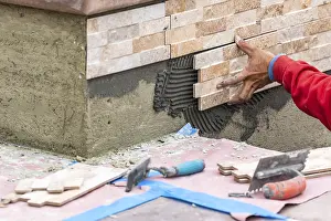 Building Construction Site Drucke: Worker installing wall tile at construction site