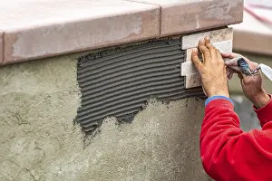 Construction Site Worker Drucke: Worker installing wall tile at construction site