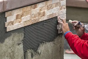 Construction Site Worker Drucke: Worker installing wall tile at construction site