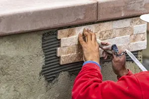 Construction Site Worker Drucke: Worker installing wall tile at construction site