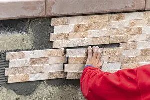 Construction Site Worker Drucke: Worker installing wall tile at construction site