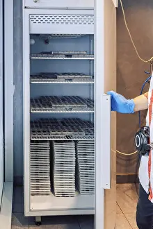Industrial Building Architecture Style Drucke: Worker opens refrigerator to store chocolates