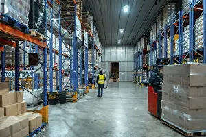 Teamwork In Industry Drucke: Workers are moving inventory using a forklift