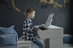 Young Boy Playing Piano Drucke: A young boy, focused and attentive