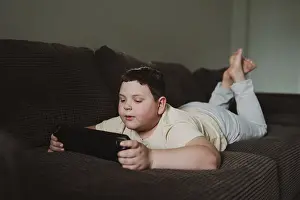 Leisure Time Activities Drucke: Young boy lying on a comfortable brown sofa