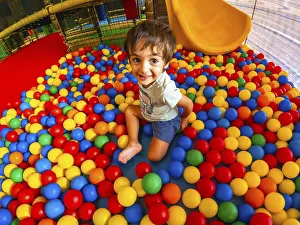 Young Boy Playing Drucke: A young boy is playing in a ball pit