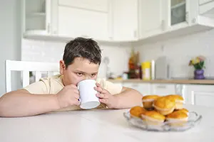 Cozy Breakfast Atmosphere Drucke: A young boy sits at a kitchen table