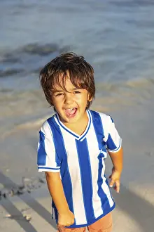 Blue Striped Shirt Drucke: A young boy is standing on the beach