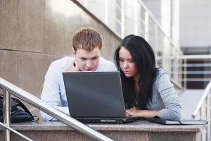 Young Couple Working On Laptop Drucke: Young couple with laptop on the steps