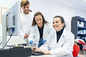 Healthcare Professionals Working Together Drucke: Three young doctors working in a scholarship in a laboratory using computer to analyse data