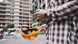 Construction Site Worker Drucke: Young Engineer using smartphone on construction site