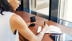 Small Business Owner Drucke: Young entrepreneur taking notes in cafe