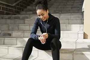 Sportsman Training Routine Drucke: Young female runner checking her pulse with an activity tracker after training