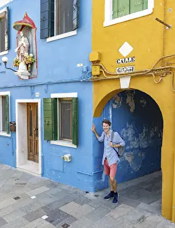 Burano Island Italy Drucke: Young man with backpack in a passageway