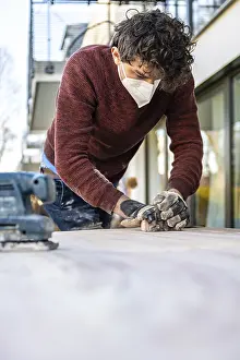 Young Man DIY Drucke: Young man doing DIY, grinding table with a grinder