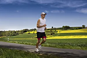 Fitness In Nature Drucke: A young man jogging through the fields