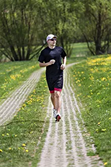 Sportsman In Action Drucke: A young man jogging through the fields