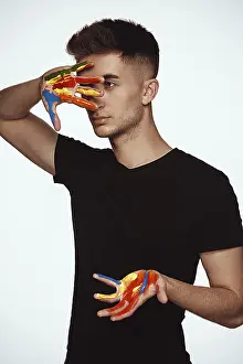 Caucasion Ethnicity Man Drucke: A young man with multi-colored paint on his hands