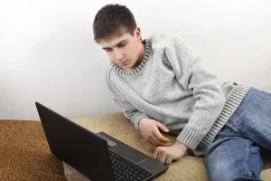 Young Man On Sofa Drucke: Young man with notebook on sofa