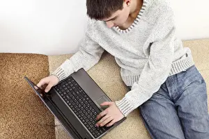 Young Man On Sofa Drucke: Young man with notebook on sofa