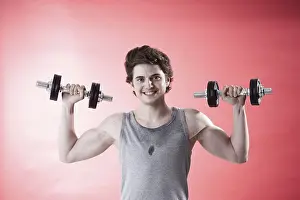 Male Muscle Buildup Drucke: Young man using dumbbells during strength training