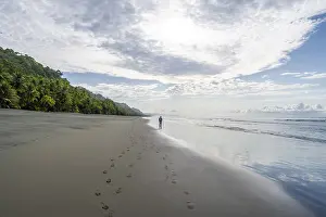 Young Man On Beach Drucke: Young man walking along a sandy beach