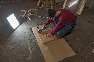 Evening Sky Atmosphere Drucke: Young man working with an angle grinder in his workshop in the evening