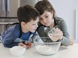 Family Cooking Together Drucke: Two young siblings engage in a baking activity