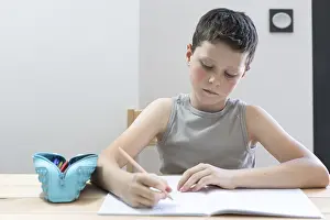 Writing Utensils Stationery Drucke: A young student intently writes in a notebook