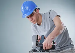 Protective Headgear Drucke: Young tradesman using a jigsaw