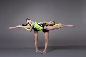 Fitness Wellbeing Exercise Drucke: Two young woman as acrobats exercise pair program on grey