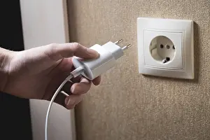 Power Supply Line Image Drucke: A young woman inserts a plug into a socket
