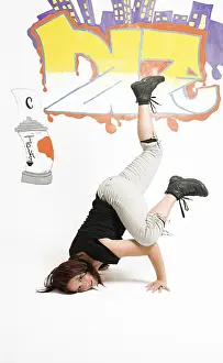 Drucke von Junge Frauen mitten in einem Breakdance-Schritt, die auf ihrem Kopf balanciert, vor einem Graffitihintergrund Zeitgenössische Kunst Drucke: Junge Frauen in der Mitte eines Breakdancing-Moves